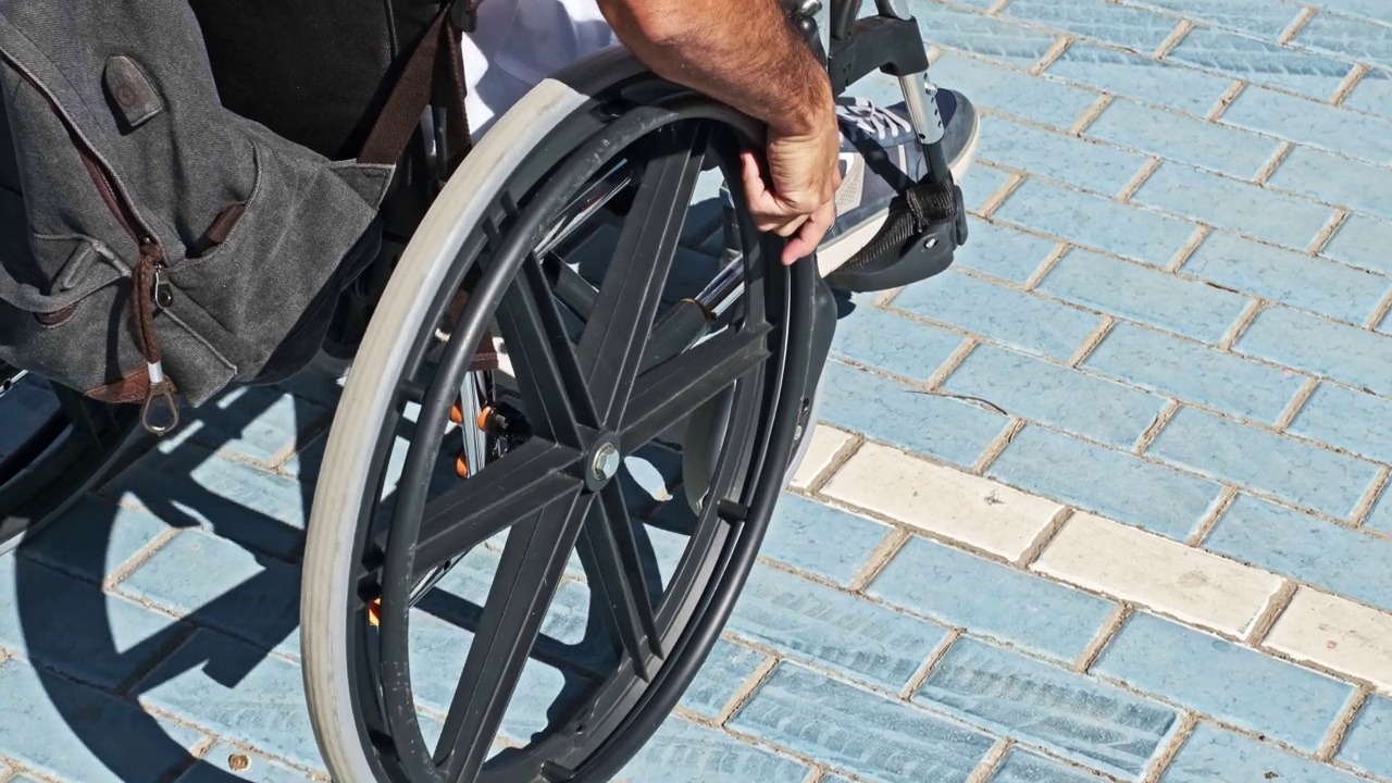 慢动作视频显示，一名黑头发、身穿白衬衫、坐轮椅的男子靠近停在残疾人停车场的他的车视频下载
