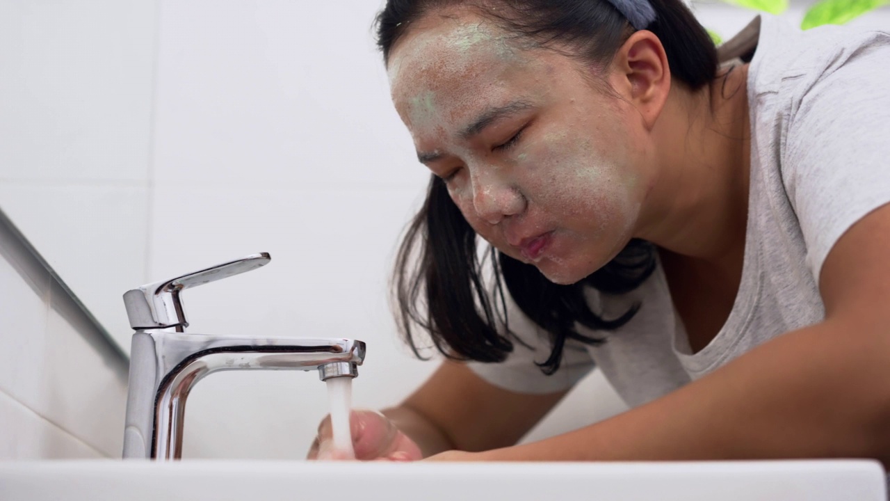 一名女子在做完面部护理后在浴室洗脸视频素材