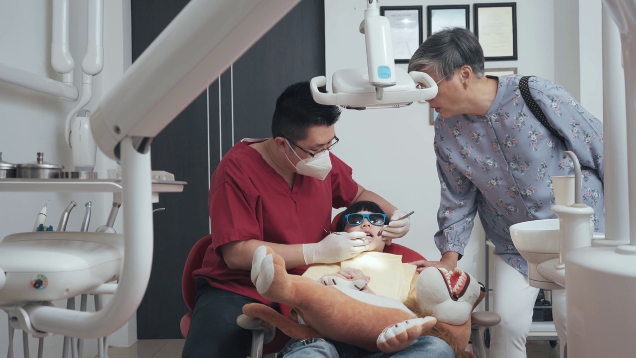 亚裔华人奶奶陪孙子去看牙医做牙齿常规检查视频素材