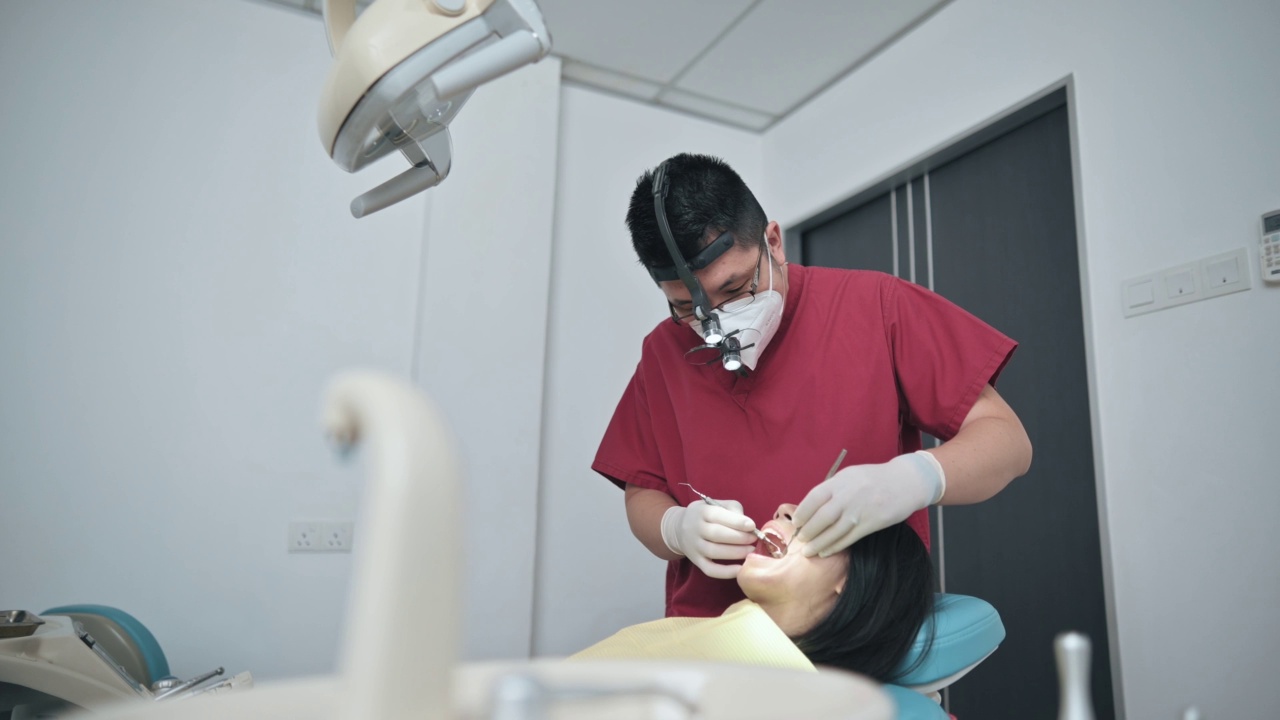 亚裔华人男牙医在牙科诊所检查女病人视频素材