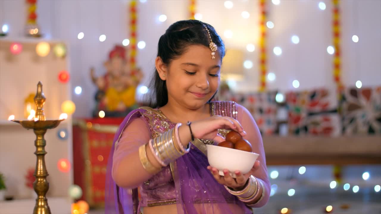 一个美丽的年轻女孩穿着民族服饰，微笑着向镜头展示糖果——排灯节视频素材
