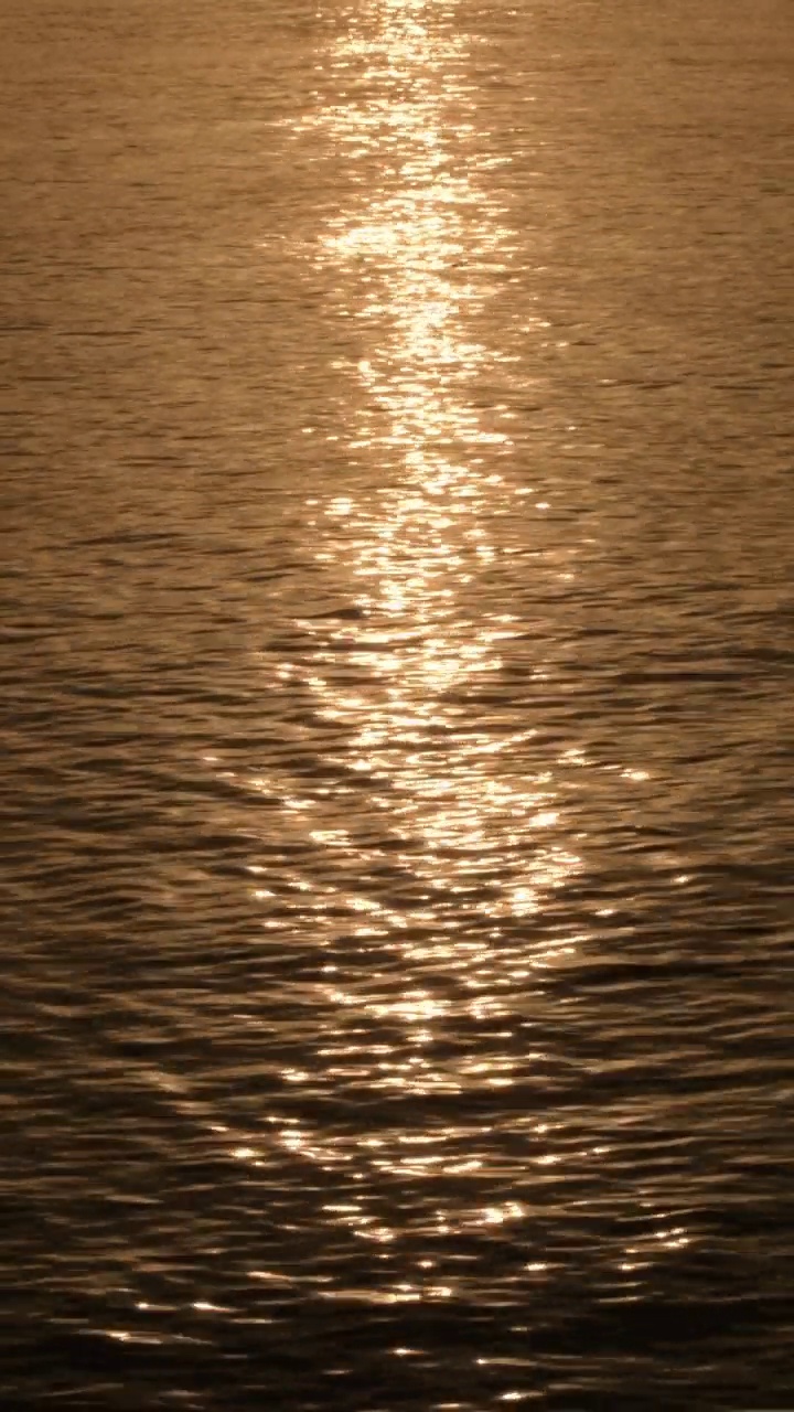 夕阳西下时，海浪中的太阳。4 k垂直视频素材