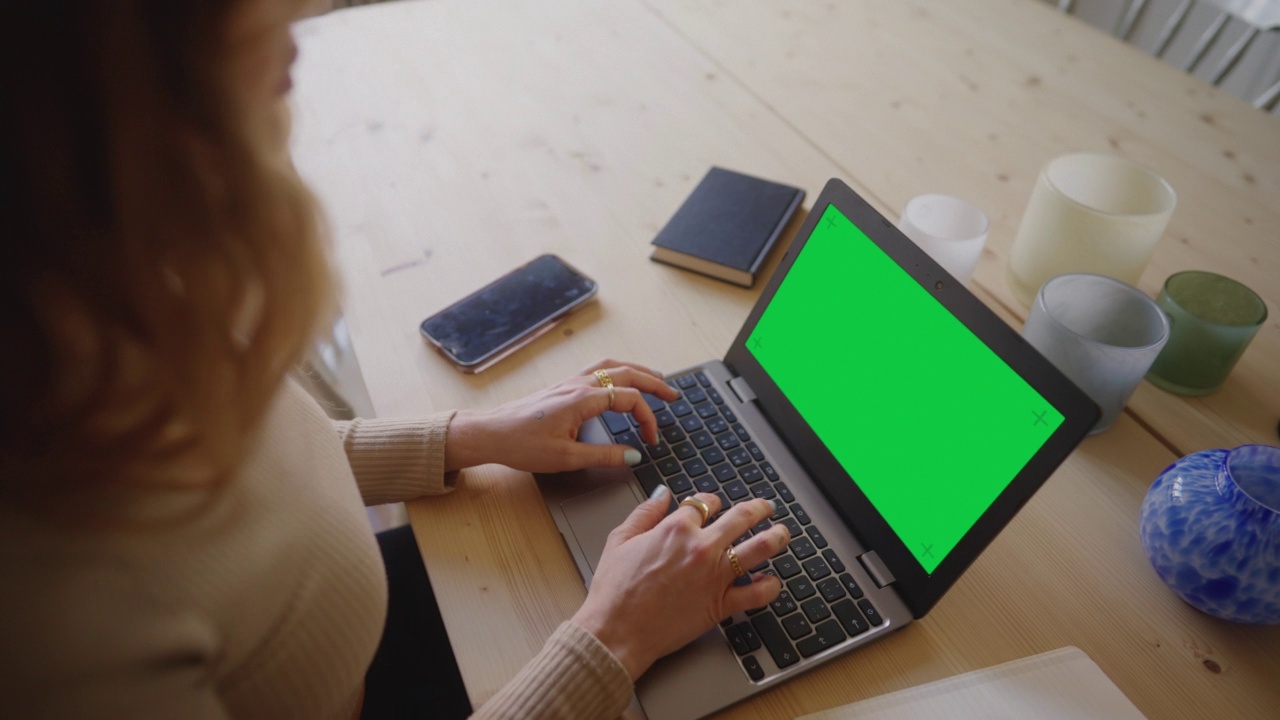 一位女士在一台色度键绿色屏幕的笔记本电脑上打字视频素材