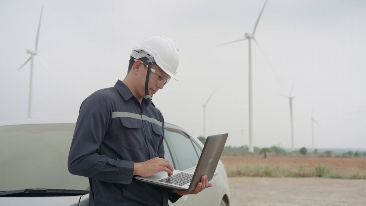 在泰国风电场，检查工程师用笔记本电脑准备和检查风力涡轮机的进展。视频素材