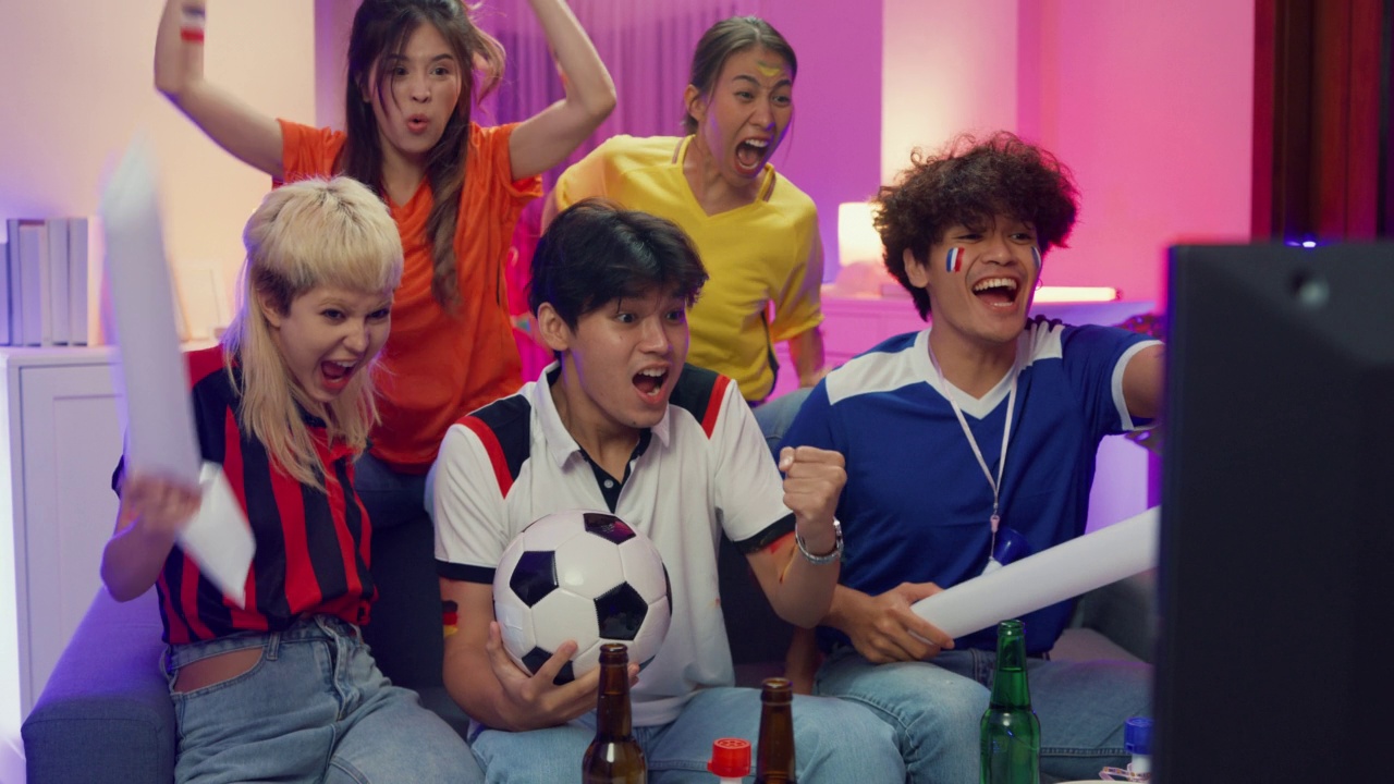 晚上，一群快乐的亚洲青少年坐在沙发上看电视上的世界杯助威运动、足球比赛。视频素材