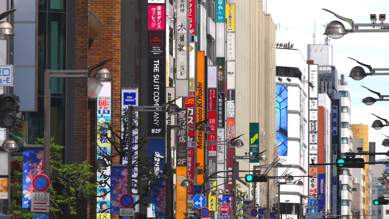 在日本东京新宿，新宿道里大道两旁的一排建筑物上悬挂着许多招牌。视频素材