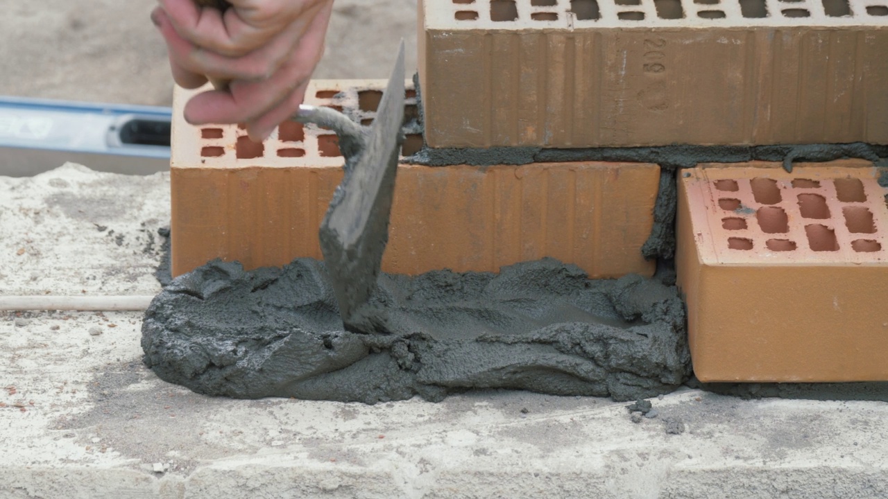 建筑工在红砖上涂水泥砂浆。砖建筑的概念视频素材