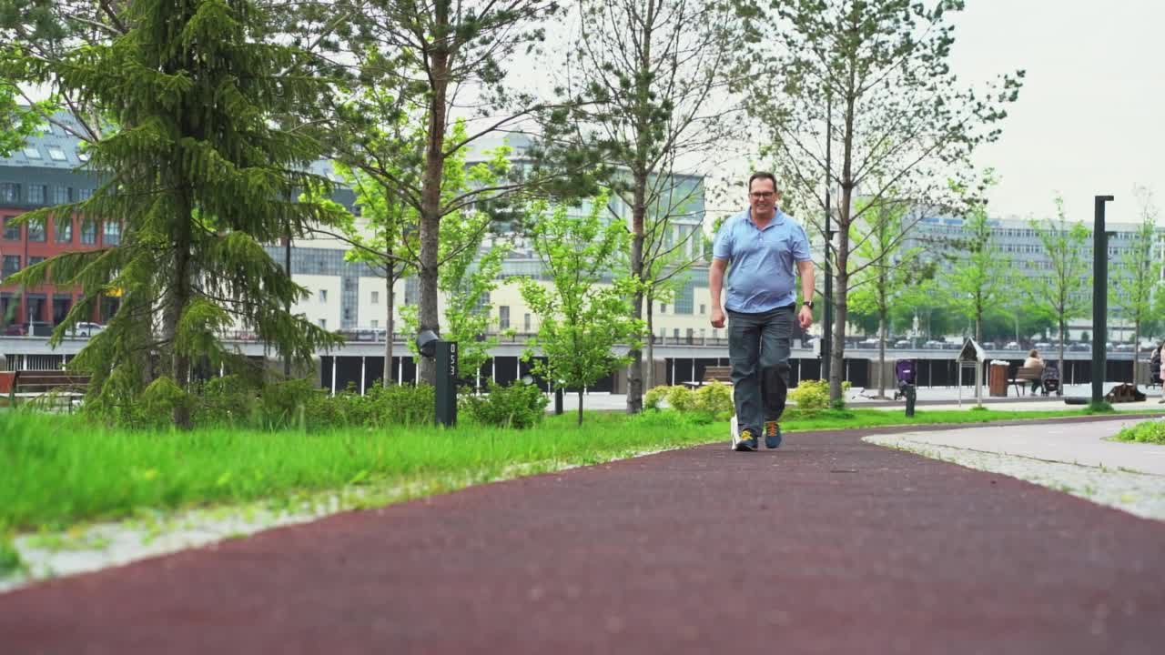 超重男子带着杰克罗素梗狗在城市公园散步视频下载