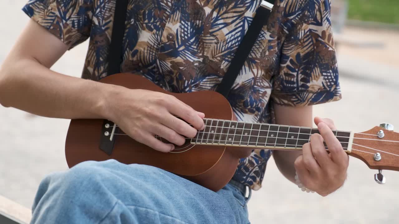 特写的无法辨认的人在街头演奏木尤克里里吉他。视频下载