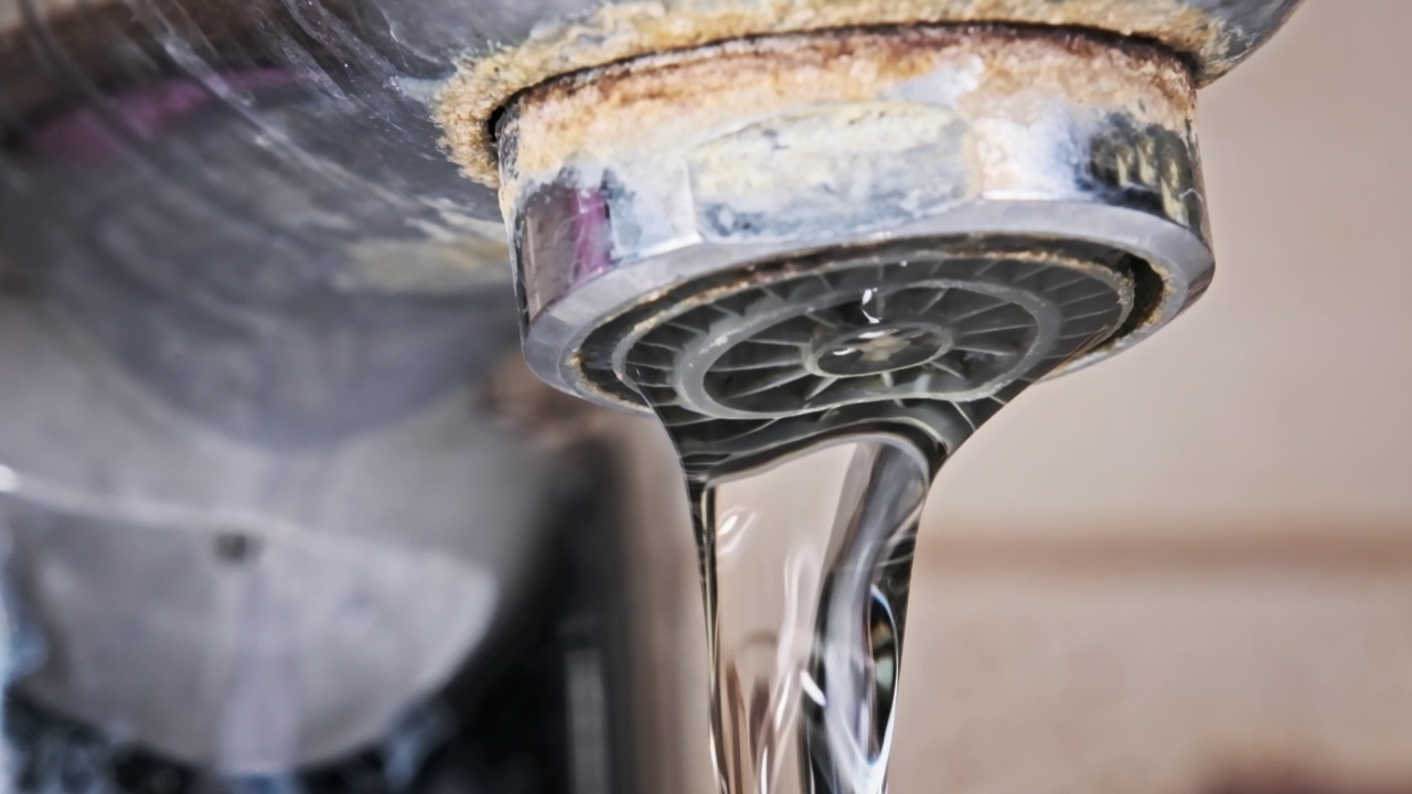 水从一个被污染的带有钙和污垢的旧水龙头流入水槽视频素材