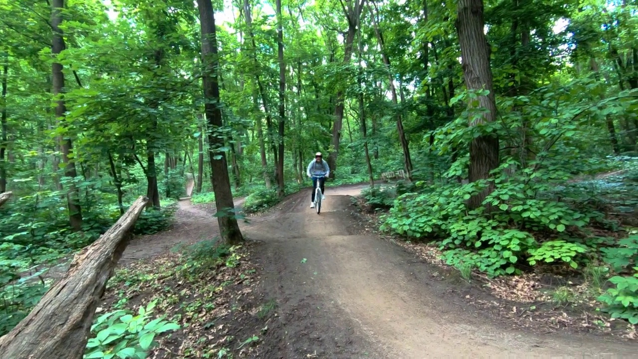 可爱的女孩沿着森林小路骑自行车视频素材