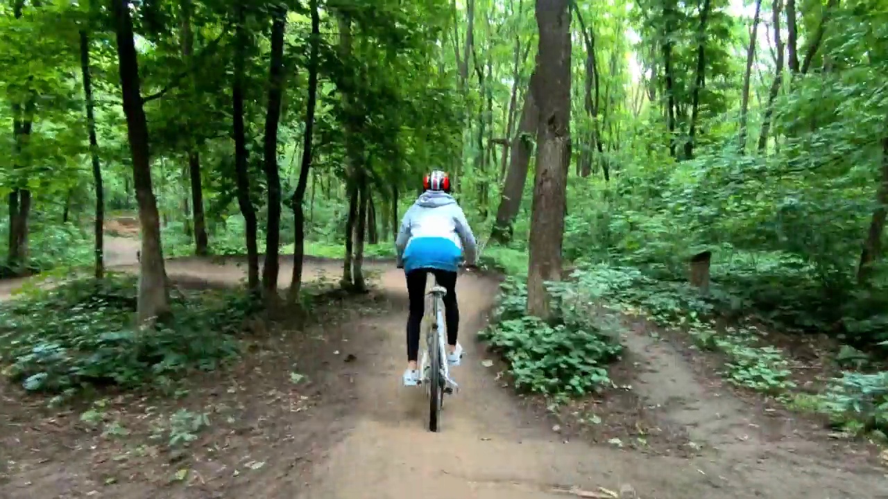 女孩在森林里的自行车道上骑车视频素材