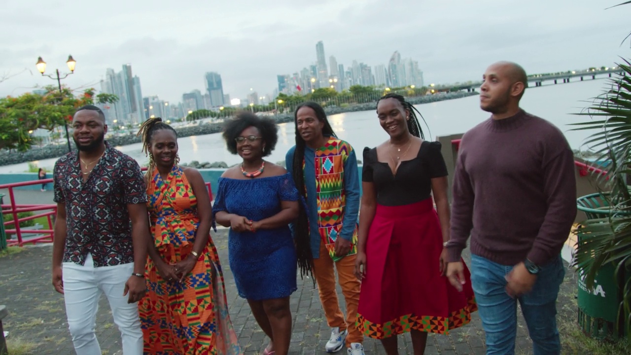 当地导游与一群愉快的、时尚的非洲裔游客一起漫步并指着地标，欣赏黄昏时分的巴拿马城视频下载