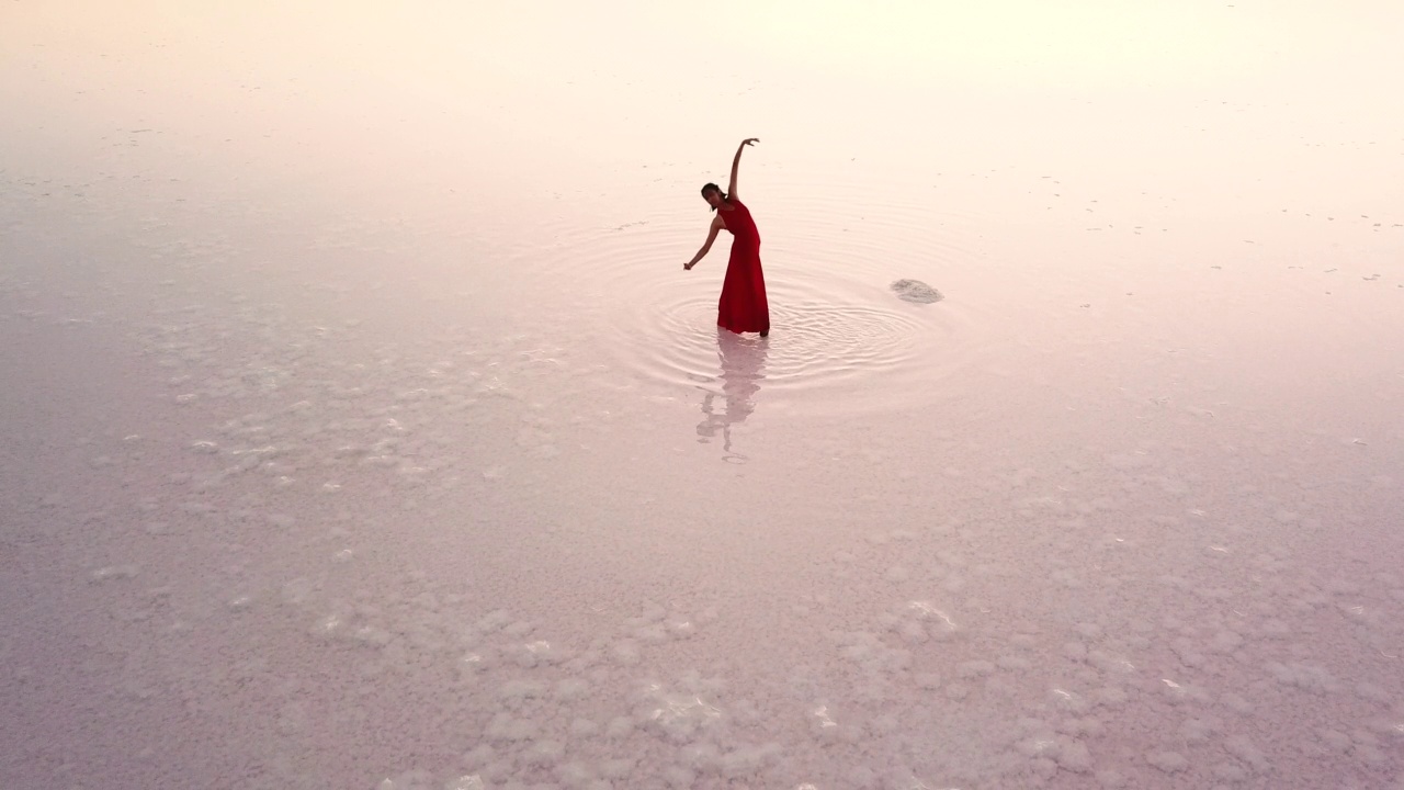 无人机拍摄的芭蕾舞者在日落时在图兹湖跳舞，以及她在水中的倒影视频素材