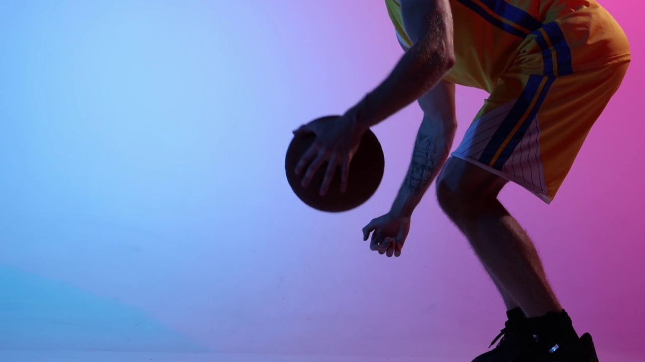 年轻男子，职业篮球运动员训练与篮球在渐变蓝粉色霓虹背景。运动，动作，动作，技能概念视频素材