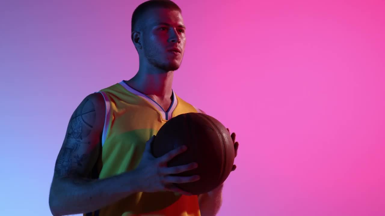 渴望胜利。职业篮球运动员拿着篮球，在渐变的蓝粉色霓虹背景下表达情感。视频素材