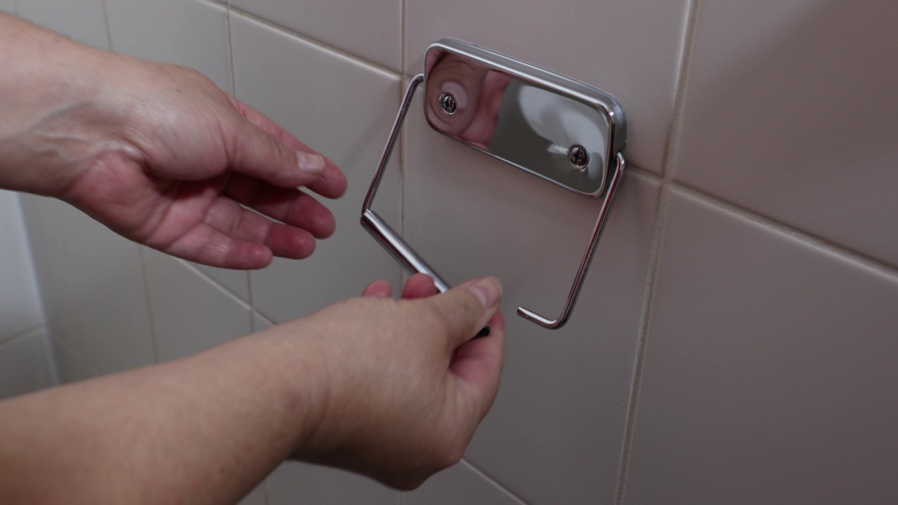 成年女性将一卷白纸放在浴室墙上的厕纸支架里视频素材