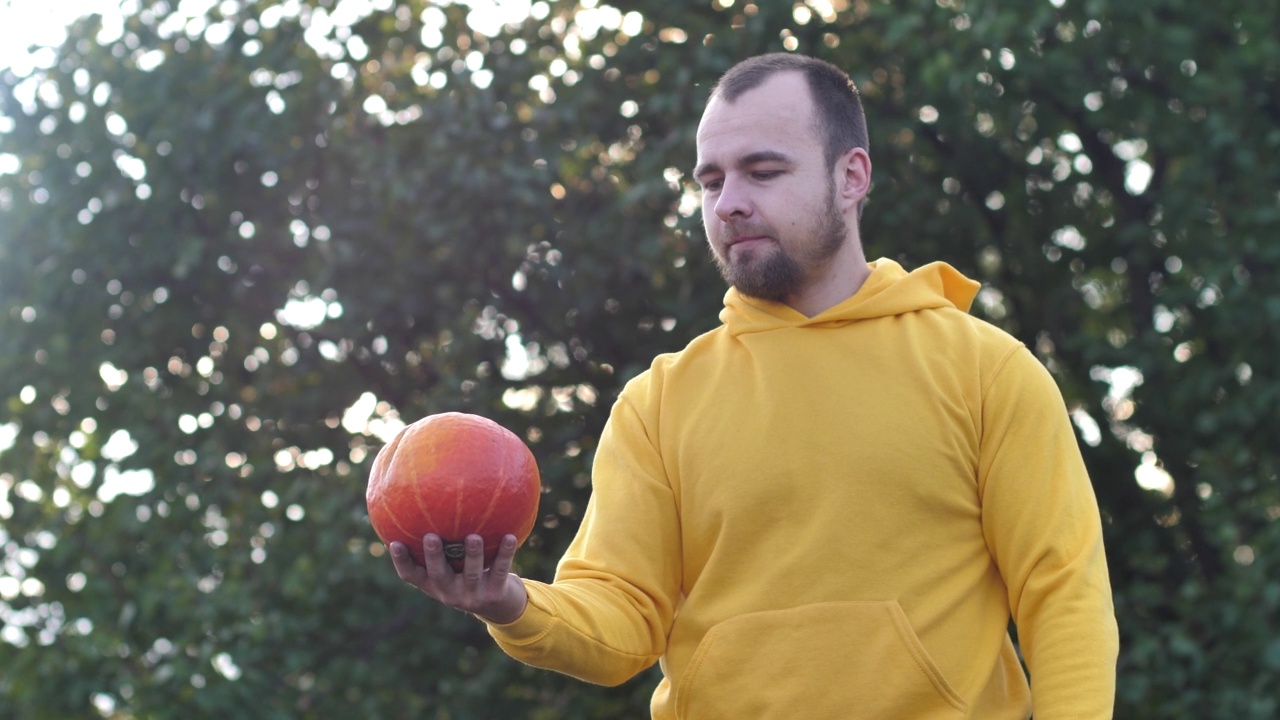 一个年轻人把南瓜当球玩。万圣节的传统象征视频素材