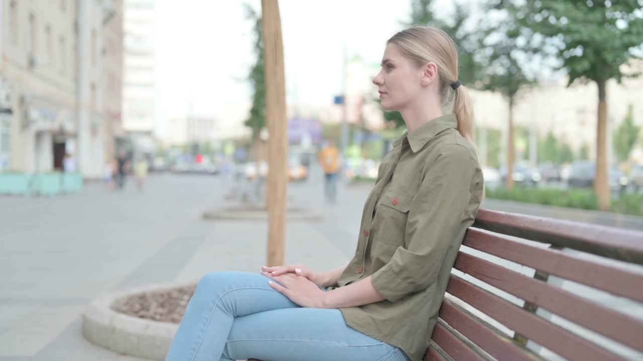 女人坐在长凳上看镜头视频素材