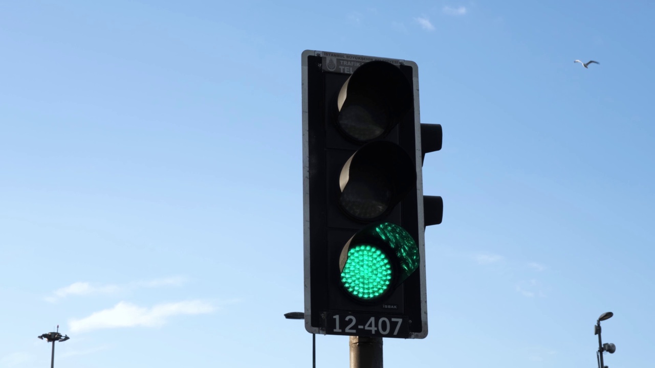 在晴朗的天空下，城市交通红灯变绿的细节视频下载