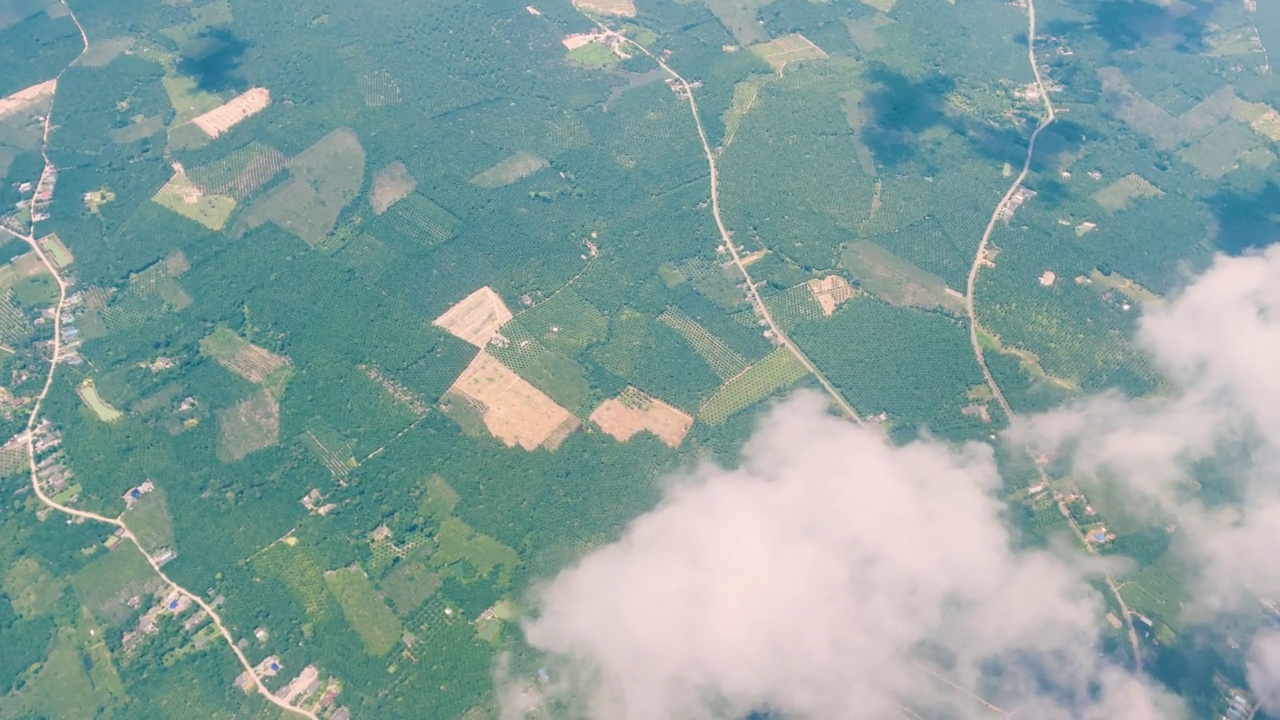 在一个阳光明媚的日子里，透过高空商业航班的窗户俯瞰东南亚的村庄、农场和稻田。视频下载