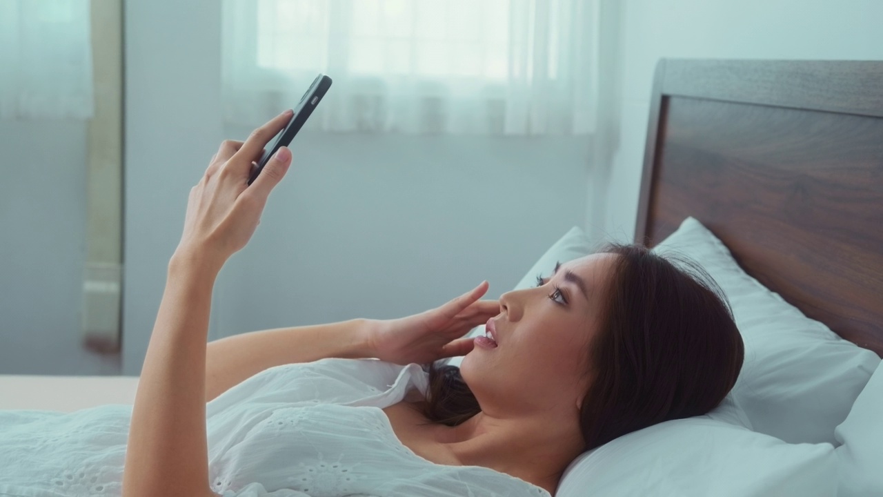 亚洲女性在卧室使用智能手机时感到眼睛疲劳视频素材