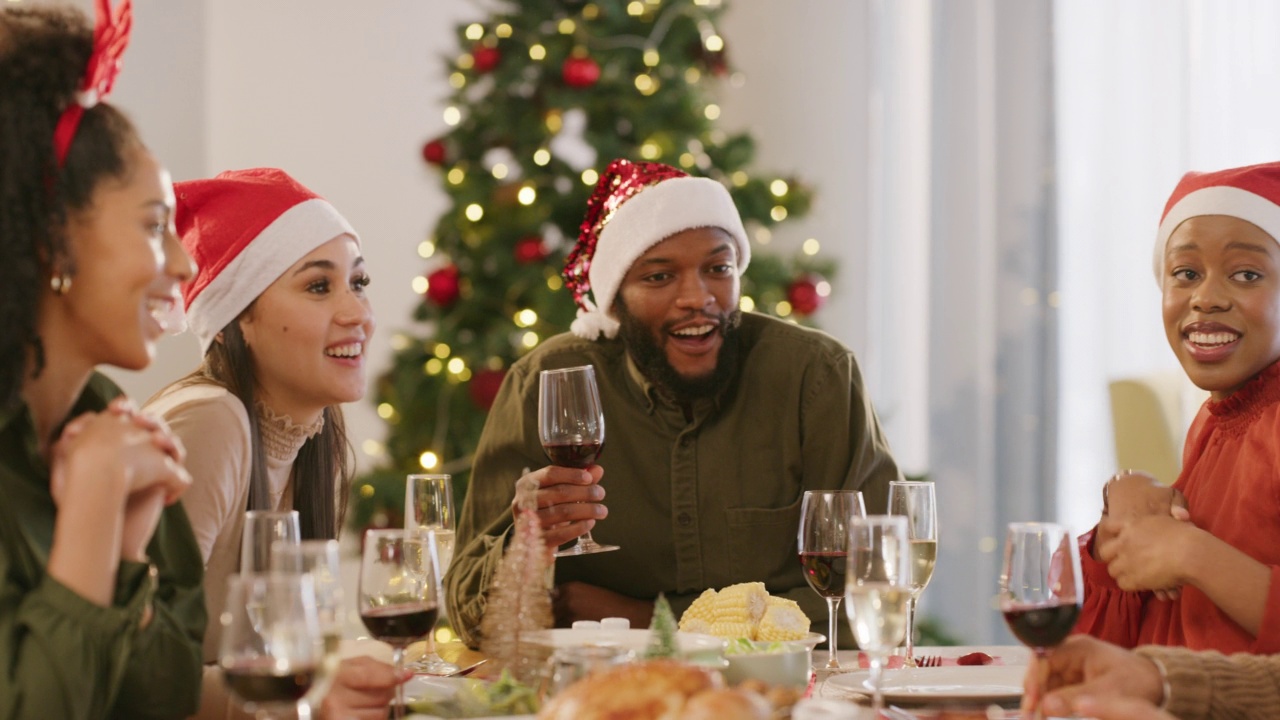 圣诞庆祝，美食派对和朋友们微笑着午餐，火鸡晚餐和鸡肉食谱在客厅的桌子上。家庭的多样性与快乐庆祝人们在假日一起吃饭视频素材