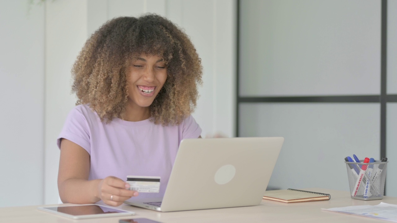 年轻的非洲妇女用笔记本电脑成功在线支付视频素材