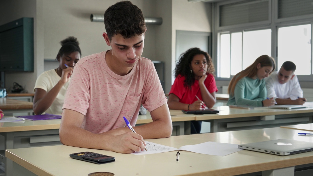 十几岁的男孩在课堂上听教授讲课，记笔记——不同种族的学生在高中大学学习视频下载