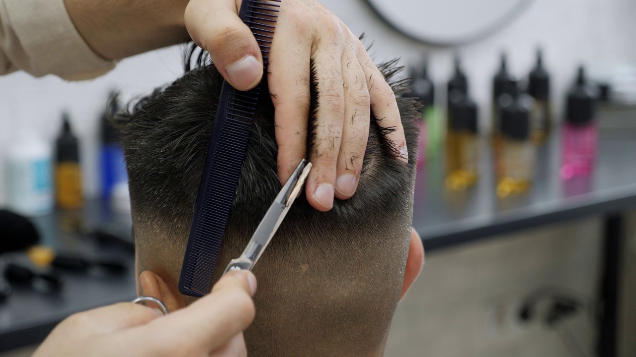 一名男子在理发店的发型师那里理发。剪刀梳子特写视频素材