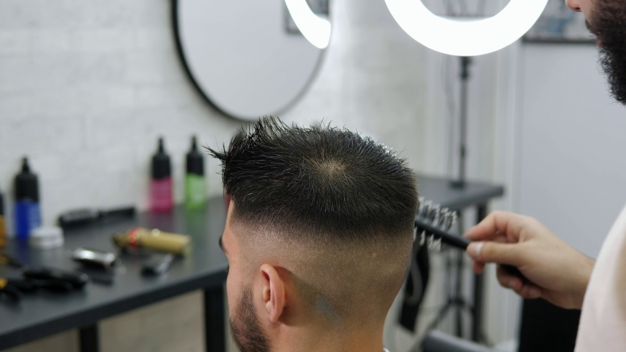一个男人在理发前为客户梳理湿头发的特写。的视频素材