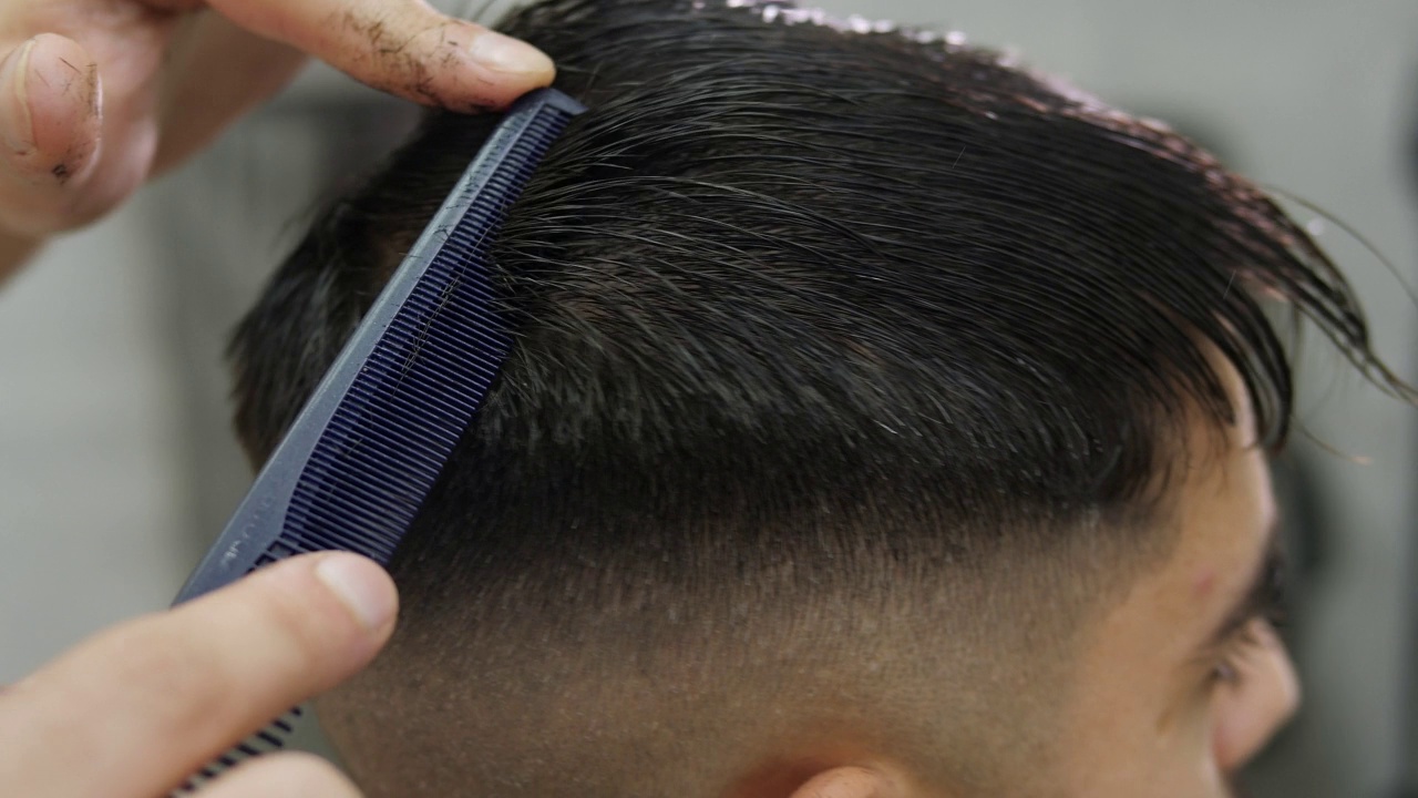 在现代理发店里，一个男理发师正在给一个男人梳头和理发。视频素材