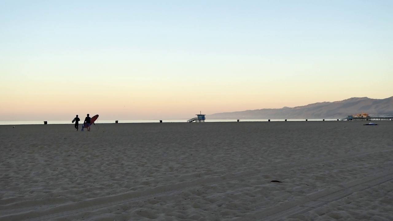 清晨，两个冲浪者在海滩上散步视频下载