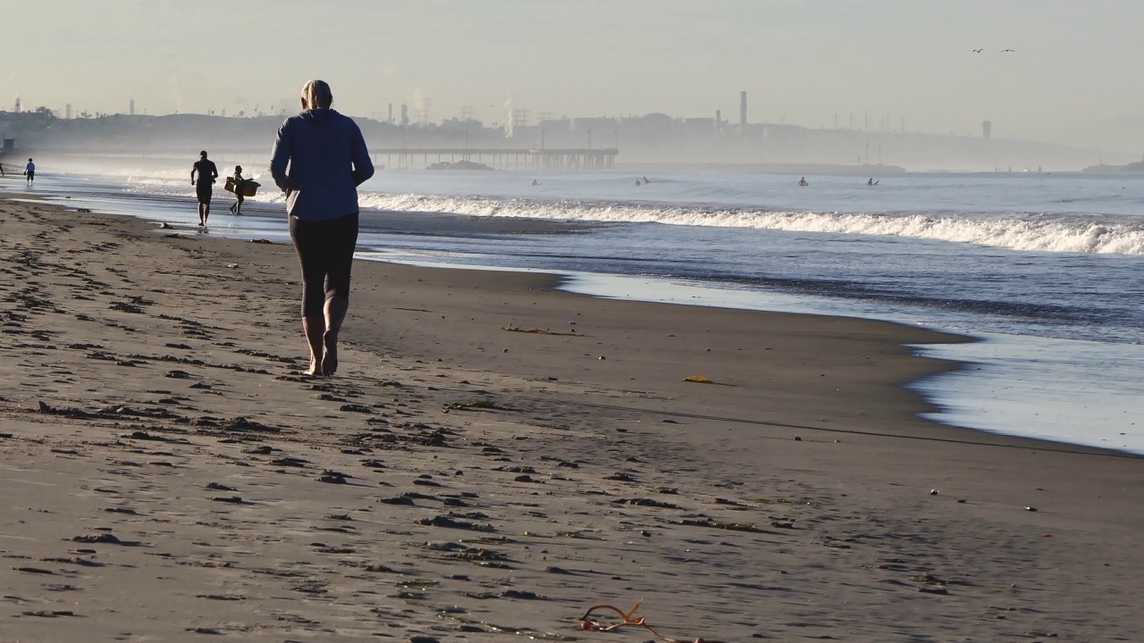 清晨在海滩与慢跑者视频下载