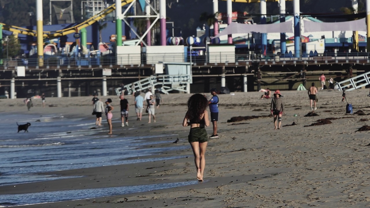 海滩上的人们，背景是色彩斑斓的游乐园视频下载