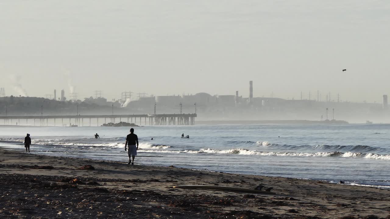 清晨，一个男人和一个女人的剪影走在海滩上视频下载