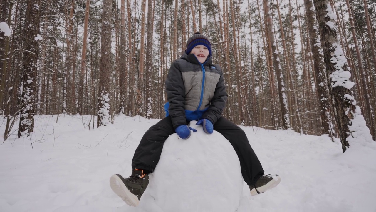 高加索小孩坐在大雪球上，微笑着扔雪球视频下载
