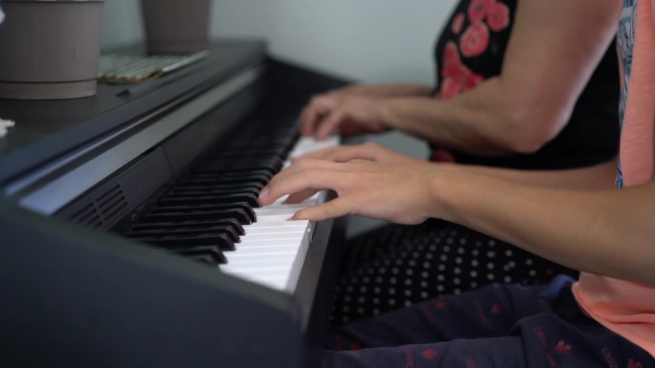 特写老年妇女教一个小男孩用乐谱弹钢琴。视频素材