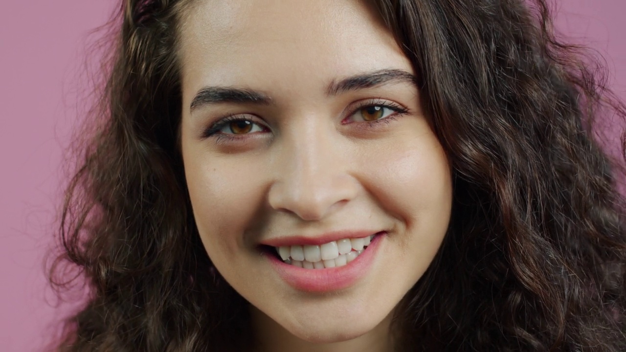 特写的快乐的年轻女子微笑和笑在粉红色的背景视频素材