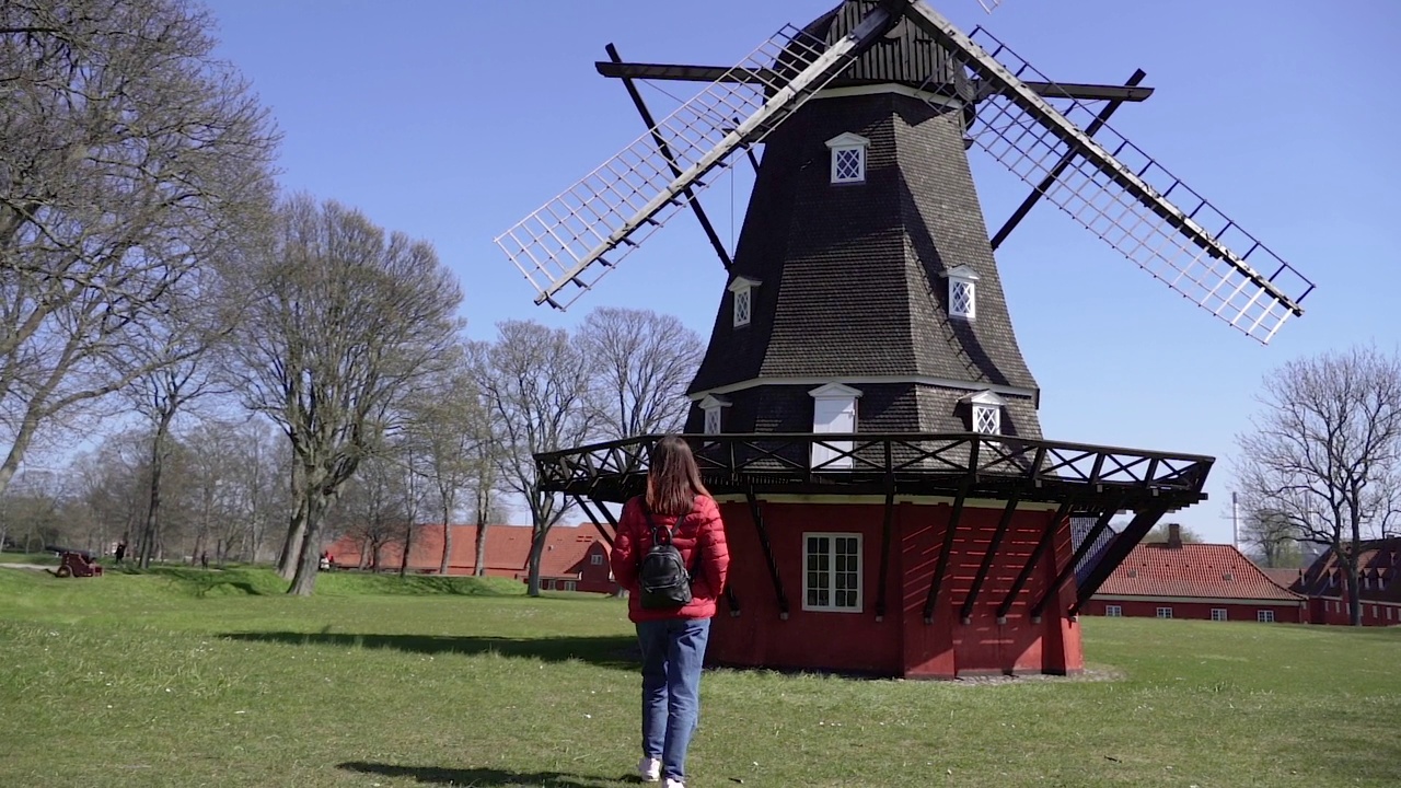 风力机。一位妇女走在一座旧风车附近。丹麦。哥本哈根。视频下载