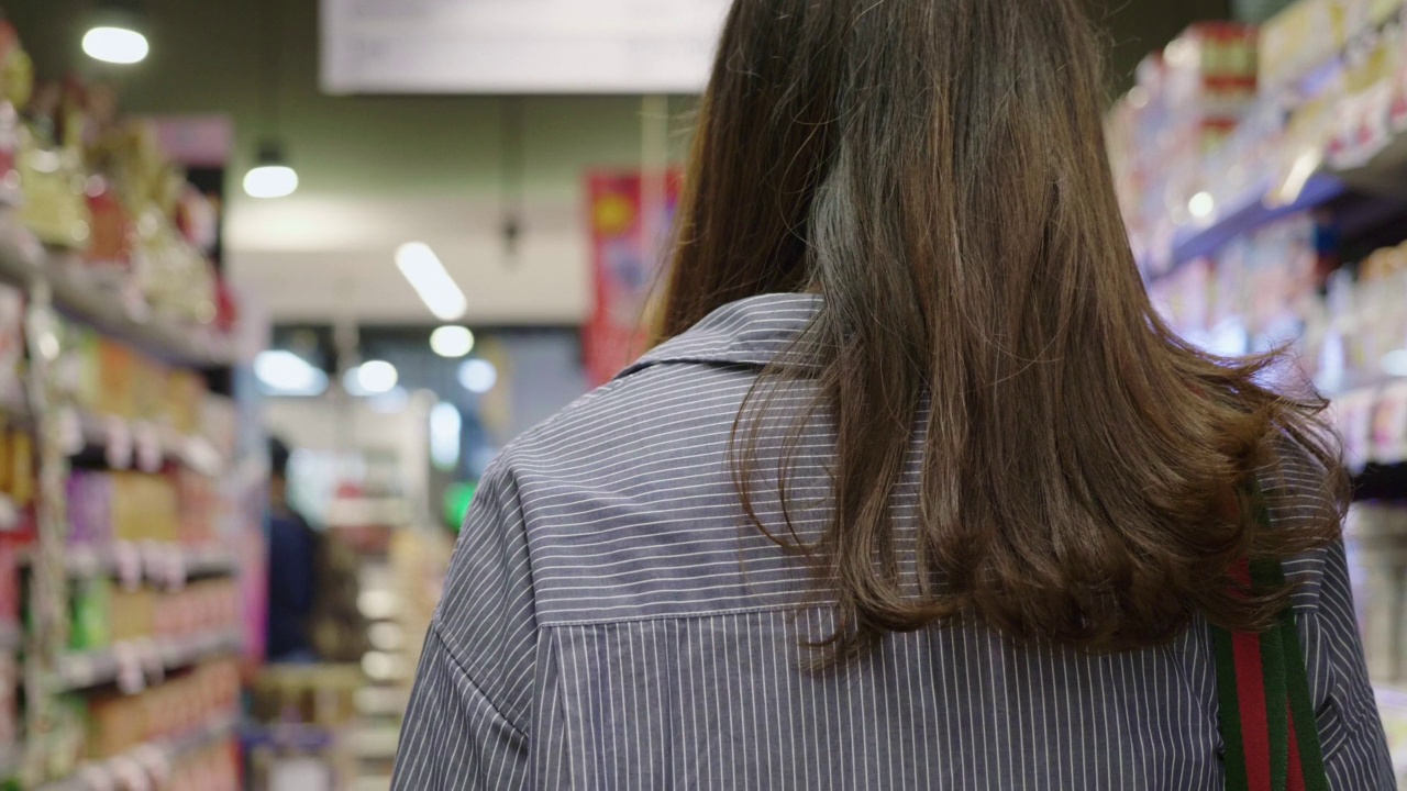 戴着防护口罩的亚洲孕妇和男婴在超市货架上挑选产品视频素材