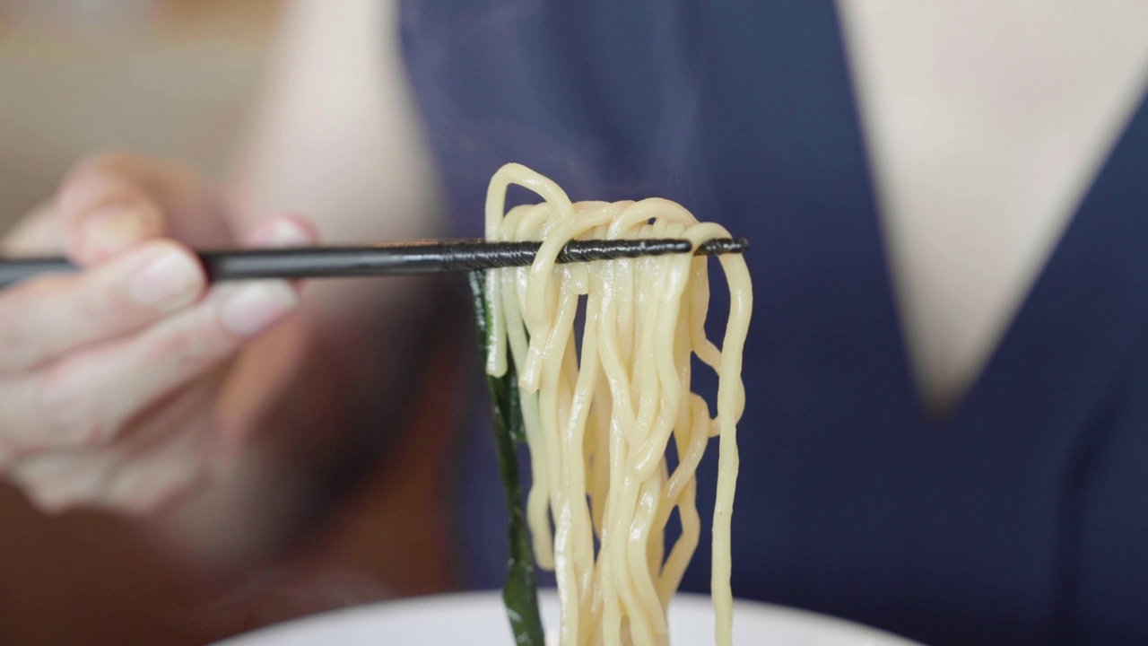 亚洲妇女在日本餐厅吃日式拉面，近距离在热面条视频素材