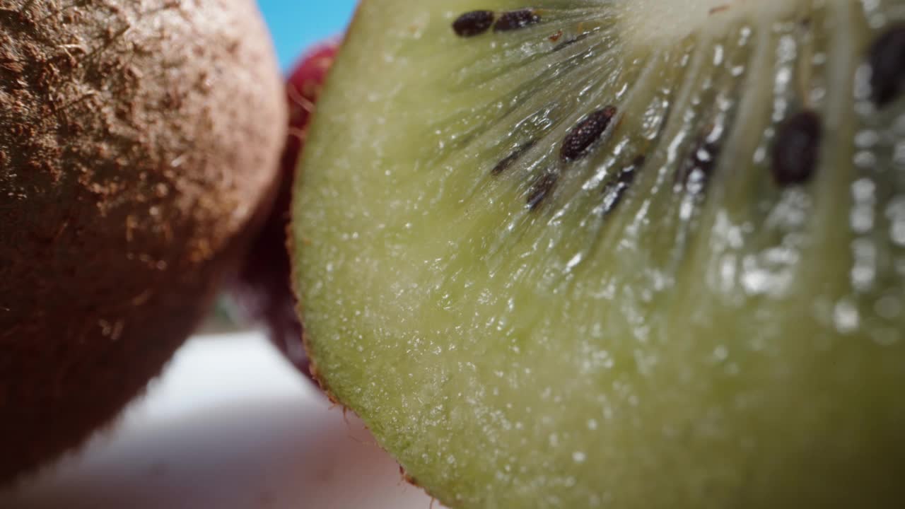 红色和绿色的果冻里面有猕猴桃和草莓块，草莓和猕猴桃放在桌子上。洋娃娃滑块极限特写。Laowa探针视频素材