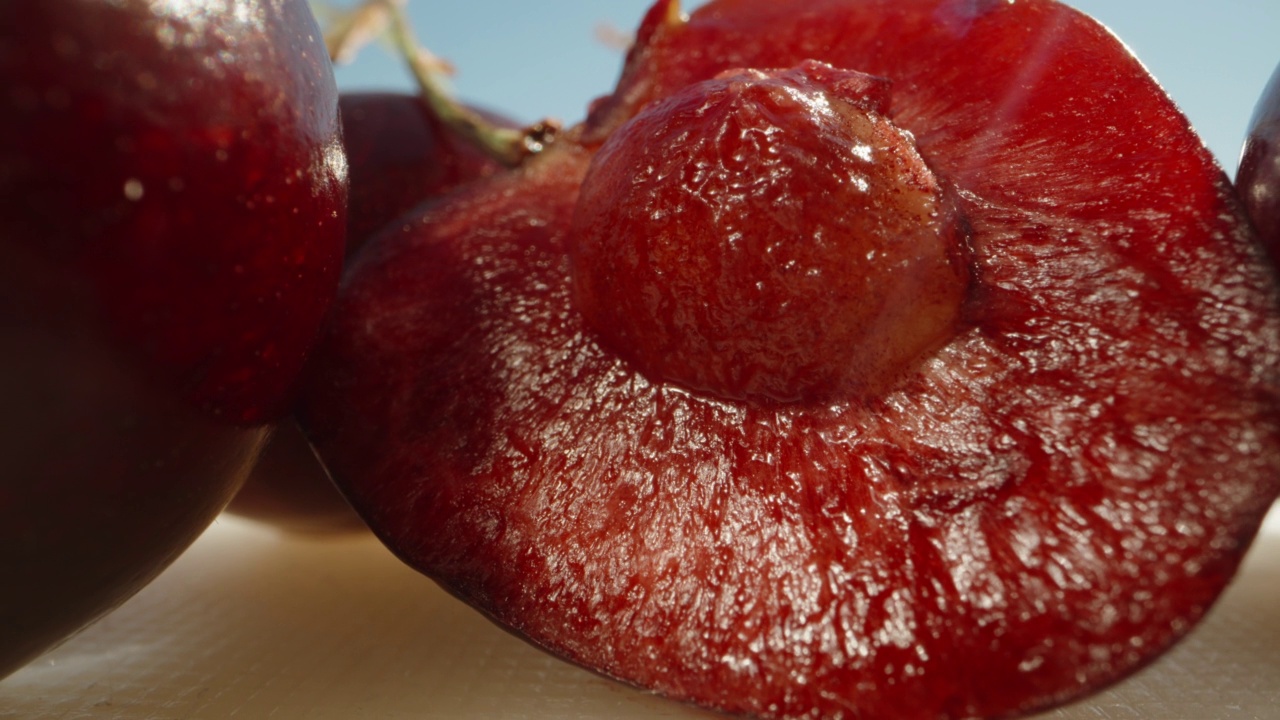 红色果冻里面有樱桃，樱桃放在桌子上。阳光,蓝天。洋娃娃滑块极限特写。Laowa探针视频素材