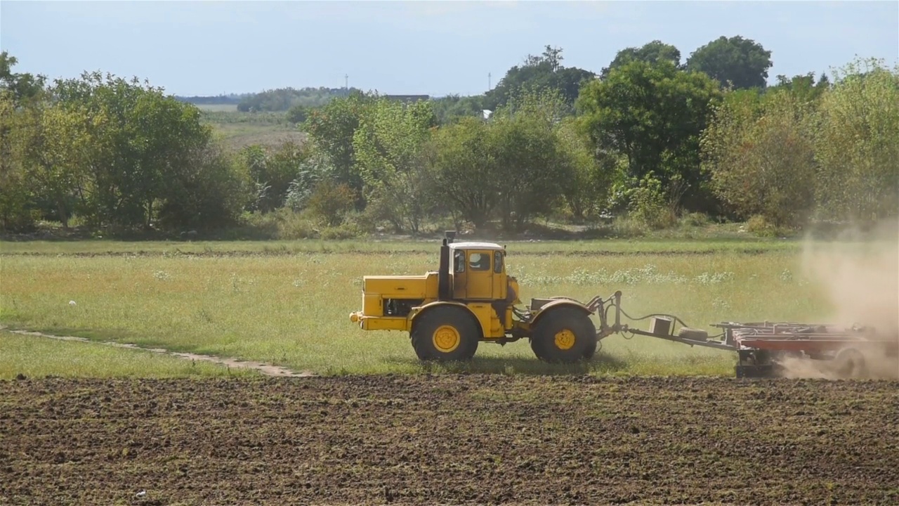 拖拉机在土地上耕作。农用拖拉机在绿地耕作中的应用。视频下载