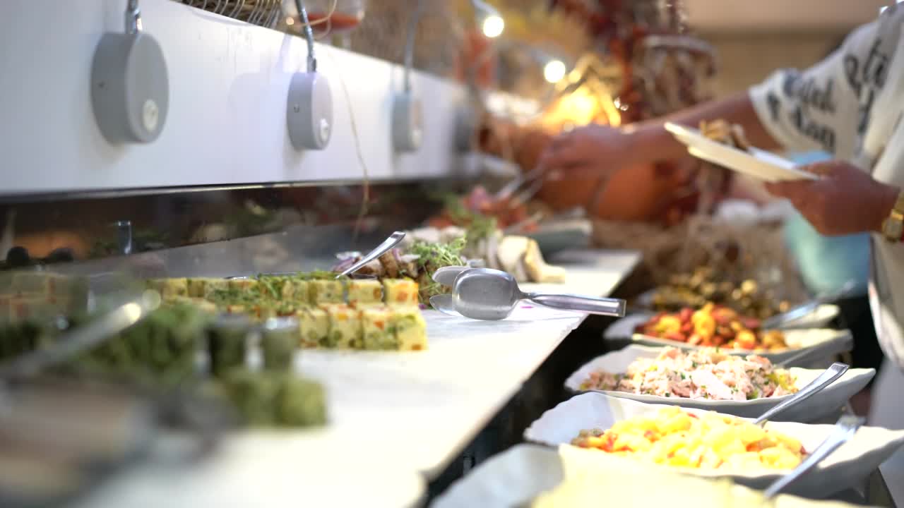 人们从酒店的自助餐柜台上取食物和沙拉视频下载