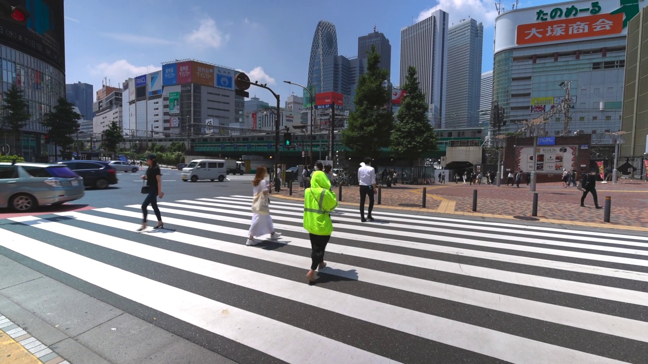 在日本东京新宿，汽车在人行横道上奔跑，人们在人行横道上穿行。视频素材