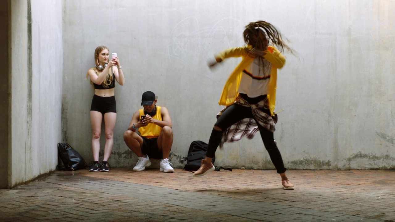 一群有影响力的舞者朋友聚在一起，一名黑人女性随着嘻哈音乐跳舞，他们通过手机进行社交媒体直播。他们跳霹雳舞，互相启发，练习编舞视频下载