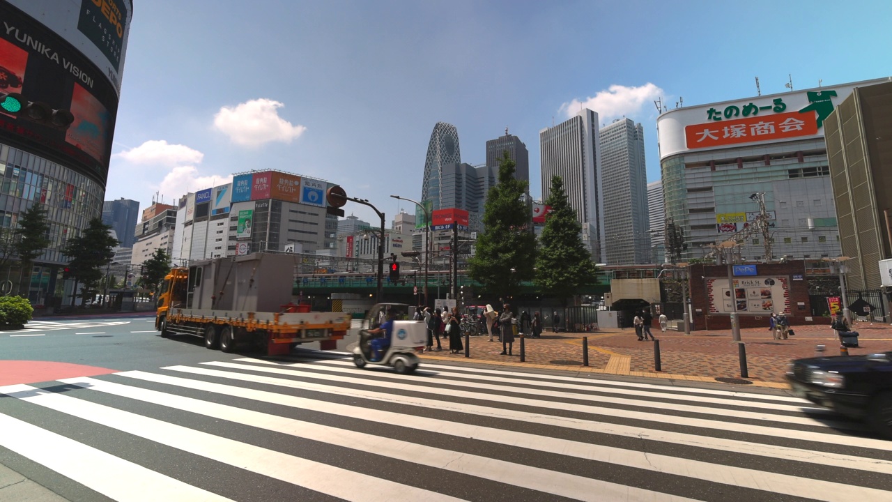 在日本东京新宿，汽车在人行横道上奔跑，人们在人行横道上穿行。视频素材