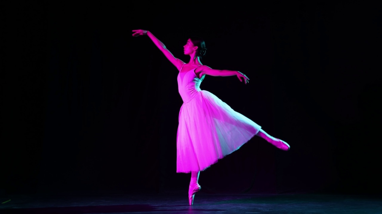 独奏。美丽而优雅的芭蕾舞演员在霓虹灯下在黑暗的剧院舞台上跳舞。艺术，幻想，灵活性，灵感概念。视频下载